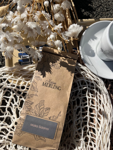 Photo d'une poche de café Moka Sidamo prise de haut, entourée de fleurs